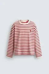 Camiseta de manga larga con diseño de rayas horizontales en color rojo y crema. Presenta cuello redondo con ribete a contraste y un pequeño parche bordado en el pecho.