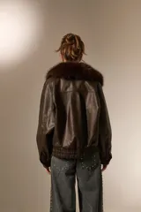 Campera de eco-cuero color marrón con cuello amplio de piel sintética al tono. Presenta un diseño de corte holgado, mangas largas y cierre frontal con botones.
