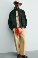 Cazadora regular fit de piel con acabado en ante color verde oscuro, de la colección especial Gabriel Azevedo x ZARA. Cuenta con cuello subido, manga larga, bolsillos de vivo en la cadera, bolsillo interior y bajo acabado con elástico. Cierre frontal con cremallera oculta por solapa con botones a presión.