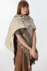 Ruana artesanal tejida en telar con lana hilada a rueca por tejedoras rurales de Uruguay. Diseño con patrón a cuadros en tonos marrón y crudo, con flecos en los extremos.