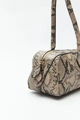 Cartera baguette cilíndrica con estampado de piel de serpiente en tonos beige y negro. Asas cortas y cierre superior con cremallera.