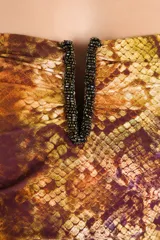 Malla enteriza strapless con estampado de serpiente en tonos marrones y dorados, con detalle de abertura en el escote bordeada con cuentas oscuras y fruncidos laterales.