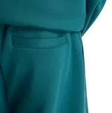 Pantalón deportivo New Balance de corte holgado, confeccionado en felpa cepillada color verde. Presenta cintura elástica con cordón ajustable, bolsillos laterales y logo de la marca estampado en la pierna izquierda.