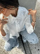 Camisa blanca de lino con cuello babero y detalles de encaje. Manga larga con puños abotonados.