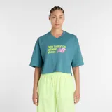Remera de corte cropped y diseño oversize, color verde azulado, con cuello redondo y mangas cortas. Presenta un estampado frontal con el logo de la marca en colores amarillo neón y rosa.