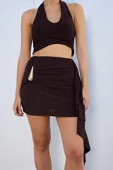 Minifalda negra con drapeado lateral y aplique metálico dorado.