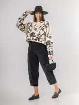 Sweater de punto con calce oversized, fondo color crudo y diseño estampado de flores en color negro. Presenta cuello redondo y mangas largas.