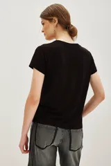 Remera de viscosa color negro, de corte clásico y manga corta, con estampa frontal de texto bordada en lentejuelas plateadas.