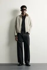 Pantalón relaxed fit negro confeccionado en tejido de algodón con estructura diagonal, estilo de cinco bolsillos y cierre frontal con cremallera y botón metálico.
