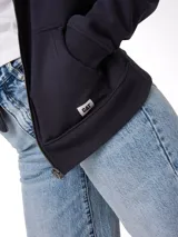 Buzo con cierre frontal completo, confeccionado en algodón y poliéster. Presenta capucha forrada, bolsillos laterales tipo canguro, puños y bajo acanalados, y etiqueta de marca en el ruedo.