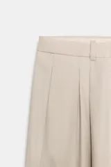 Pantalón de tiro alto con pierna ancha, confeccionado con detalle de pinzas en el delantero, bolsillos laterales y cierre frontal con cremallera y gancho metálico.