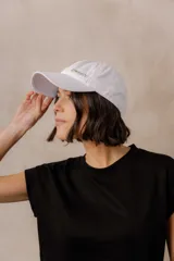 Gorra estilo baseball de algodón con efecto lavado, color blanco, con detalle de logo metálico en el frente.
