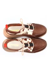 Zapato deportivo abierto en el talón, confeccionado en cuero liso marrón con detalles de cuero con pelo estampado tipo animal print en la parte superior. Presenta cierre con cordones, perforaciones decorativas en la puntera y una suela de plataforma color beige.