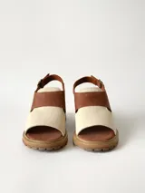 Sandalias de cuero combinadas en color marrón y crudo, con suela track y taco bajo. Tienen tira ajustable con hebilla en el talón.