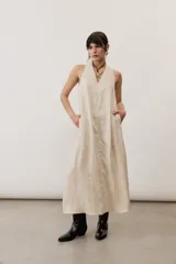 Vestido largo marrón, sin mangas, con cuello halter y bolsillos laterales.