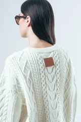 Sweater de punto color bordó con diseño de trenzas y relieves. Presenta cuello redondo, mangas largas y terminaciones acanaladas en puños y ruedo.