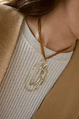Collar con dije de bronce de diseño orgánico y abstracto, compuesto por dos formas elípticas entrelazadas, suspendido de un cordón de cuero marrón.