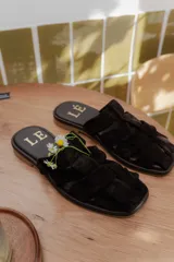 Sandalias de cuero con diseño de tiras entrelazadas, estilo jaula, con suela plana y cierre de hebilla lateral.