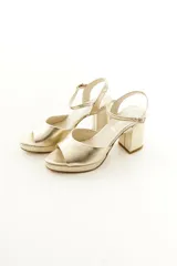 Sandalias de taco grueso y plataforma delantera, confeccionadas en cuero vacuno color dorado con tira en la parte frontal y correa ajustable al tobillo.