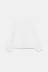 Camisa blanca de manga larga con cuello redondo. Presenta detalles de entredoses y jaretas verticales en el delantero, y cierre de botones en la espalda.
