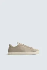 Zapatilla urbana de hombre confeccionada en piel con acabado de serraje, diseño minimalista con cordonera oculta y suela de goma a contraste.