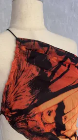 Minivestido con estampado de mariposas en tonos naranja y negro. Diseño ajustado con escote halter asimétrico y abertura en la cintura.