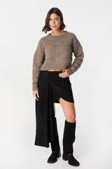 Falda de cuero marrón con diseño asimétrico, presenta un detalle de lazo frontal drapeado que crea una caída lateral más larga.