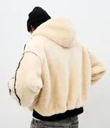 Campera de fleece color beige con diseño de paneles, costuras expuestas en color negro y cierre frontal. Posee cuello alto, mangas largas con puños elásticos y forro interior.