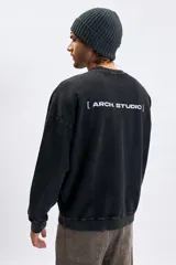 Sudadera de cuello redondo con efecto lavado, color gris oscuro, con estampa tipográfica blanca en la espalda.