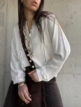 Camisa clásica blanca de manga larga con detalles de vainicas verticales y encaje, cuello mao y cierre frontal con botones.