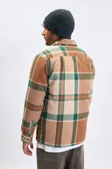 Sobrecamisa de franela con estampado de cuadros en tonos marrones y verdes, cuenta con cierre frontal, cuello clásico y bolsillos con solapa en el pecho.