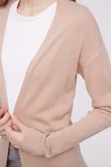 Saco tipo cárdigan abierto de tejido de punto, con mangas largas y bolsillos frontales aplicados.