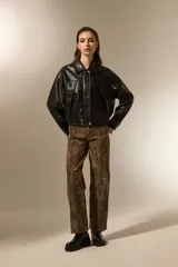 Campera de eco-cuero color negro, con cuello clásico, cierre frontal y puños con elástico. Presenta un diseño de corte holgado con costuras verticales decorativas.