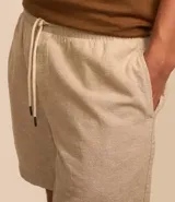 Bermuda masculina color beige claro, con textura, cintura elástica ajustable con cordón y bolsillos laterales.