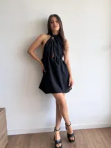 Vestido corto negro con escote halter y espalda descubierta. Presenta un corte a la cintura con falda acampanada.