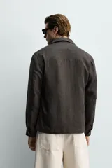 Sobrecamisa relaxed fit confeccionada en tejido de lino de color negro, con cuello solapa, manga larga con puño abotonado, bolsillos de plastrón en la cadera y cierre frontal de botones.