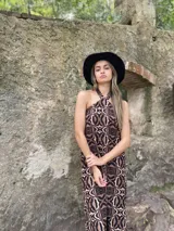 Vestido largo de corte recto con estampado abstracto en tonos marrón y beige, cuello halter y espalda descubierta.