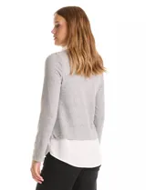 Buzo combinado de hilado fino color gris, con cuello en V y mangas largas. Presenta una pieza inferior y cuello tipo solapa en tela blanca que simula una camisa debajo.