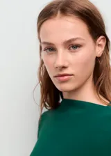 Vestido corto de color verde esmeralda, con cuello barco, manga larga y diseño entallado con detalles de fruncidos en los laterales.