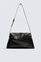 Bolso bandolera de piel color marrón oscuro, con solapa y cierre de imán y cremallera. Incluye un bolsillo interior con cremallera y un bolsillo plano. Tiene asa de hombro ajustable.