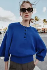 Jersey de punto liso color azul, con cuello redondo, botones delanteros y manga ancha por debajo del codo.