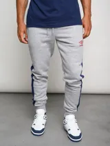 Pantalón de jogging gris con recortes laterales en azul marino y logo de Umbro en rojo.