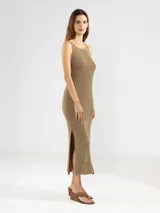 Vestido midi sin mangas, confeccionado en punto jersey con hilo Lurex que aporta un brillo sutil. Presenta escote bote redondeado y aberturas laterales en el ruedo.
