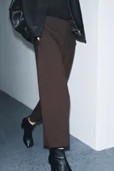 Pantalón de tiro medio confeccionado en viscosa, con corte recto y largo tobillero. Presenta cintura con trabillas, bolsillos laterales y bolsillos de vivo en la parte trasera. Cierre frontal mediante cremallera, botón y ganchos metálicos.