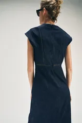 Vestido midi de denim azul oscuro, con escote en V, mangas cortas y detalles de entredoses en el escote y la cintura. Cuenta con cierre trasero con cremallera oculta.