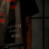Remera de manga corta con efecto lavado ácido y corte boxy fit, color negro. Presenta un gran estampado frontal con un escudo de estilo automovilístico y la frase "Need $$ For A Fagade".