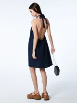 Vestido corto azul marino de tencel con corte evasé, cuello halter con lazo ajustable y espalda descubierta.