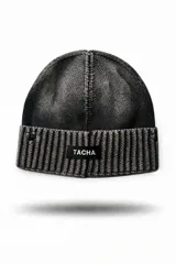 Gorro tipo beanie de tejido de punto con efecto degradado en color negro. Presenta una estructura de doble textura con base lisa y borde acanalado, e incluye una etiqueta frontal con el logo de la marca Tacha.
