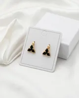 Aros tipo argolla pequeña con dije en forma de trébol o flor estilizada, con borde dorado y centro esmaltado en color negro.