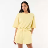 Pantalón corto de felpa color amarillo pastel, de tiro medio con cintura elástica ajustable mediante cordón y diseño holgado.